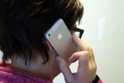 En person håller upp en vit i-phone mot sitt öra.