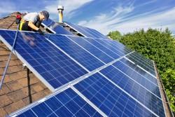 En man sätter upp panel för solceller på ett tak