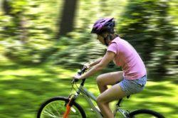 En person i rosa t-shirt cyklar så snabbt genom skogen att omgivningen är suddig.