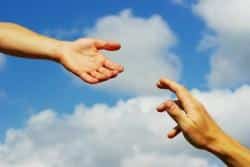 Två händer sträcks mot varandra framför en molnig himmel