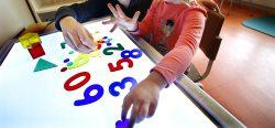 Förskolebarn leker med siffror på ett ljusbord