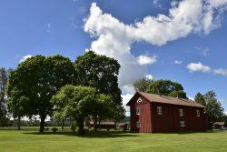 Vy över en gammal röd byggnad på hembygdgården i Ransäter