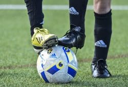 Två fötter i fotbollsskor står på en fotboll
