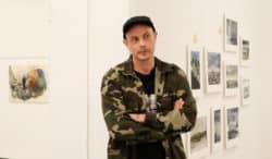 Artisten Petter står med armarna i kors framför sin konst.
