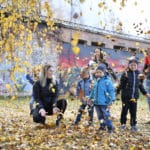 Barnfamilj som leker utomhus med löv.