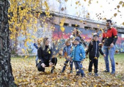 Barnfamilj som leker utomhus med löv.