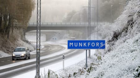 Bil kör på vinterväg intill Munkforsskylt