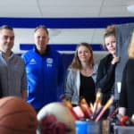 Sex personer står framför sportartiklar och målarartiklar.