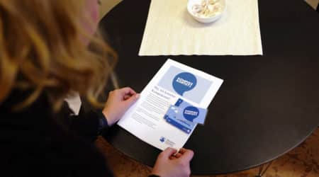 Person står lutad över dokument och kort med titeln Kompiskortet.